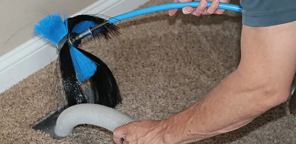 Dryer vent cleaning technician brushing lint from a vent line in Newark, NJ