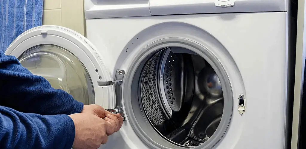 Washing machine repair handyman checking a front-load washer door and latch in Newark, NJ