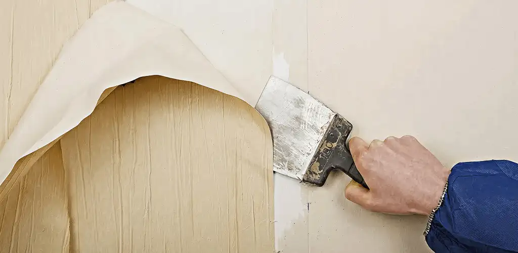 Handyman removing wallpaper with a scraper for wall preparation in Newark, NJ