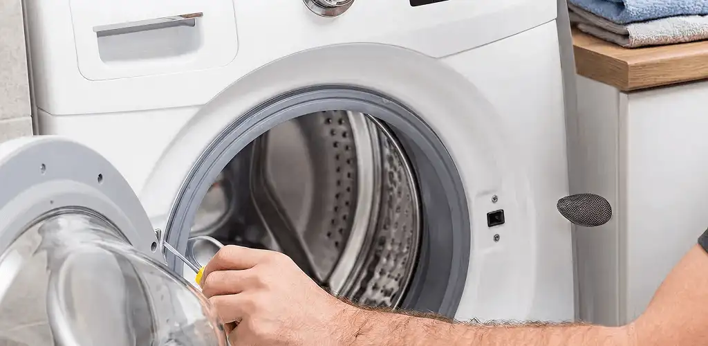 Handyman repairing a front-load washing machine and inspecting the drum in Newark, NJ