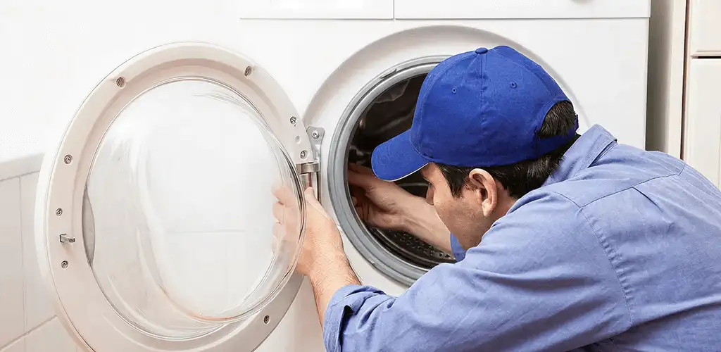 Washing machine repair handyman inspecting a front-load washer drum in Newark, NJ