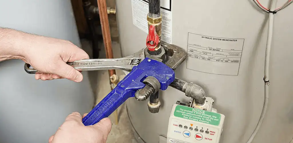 Water heater repair technician tightening the shutoff valve and supply line in Newark, NJ